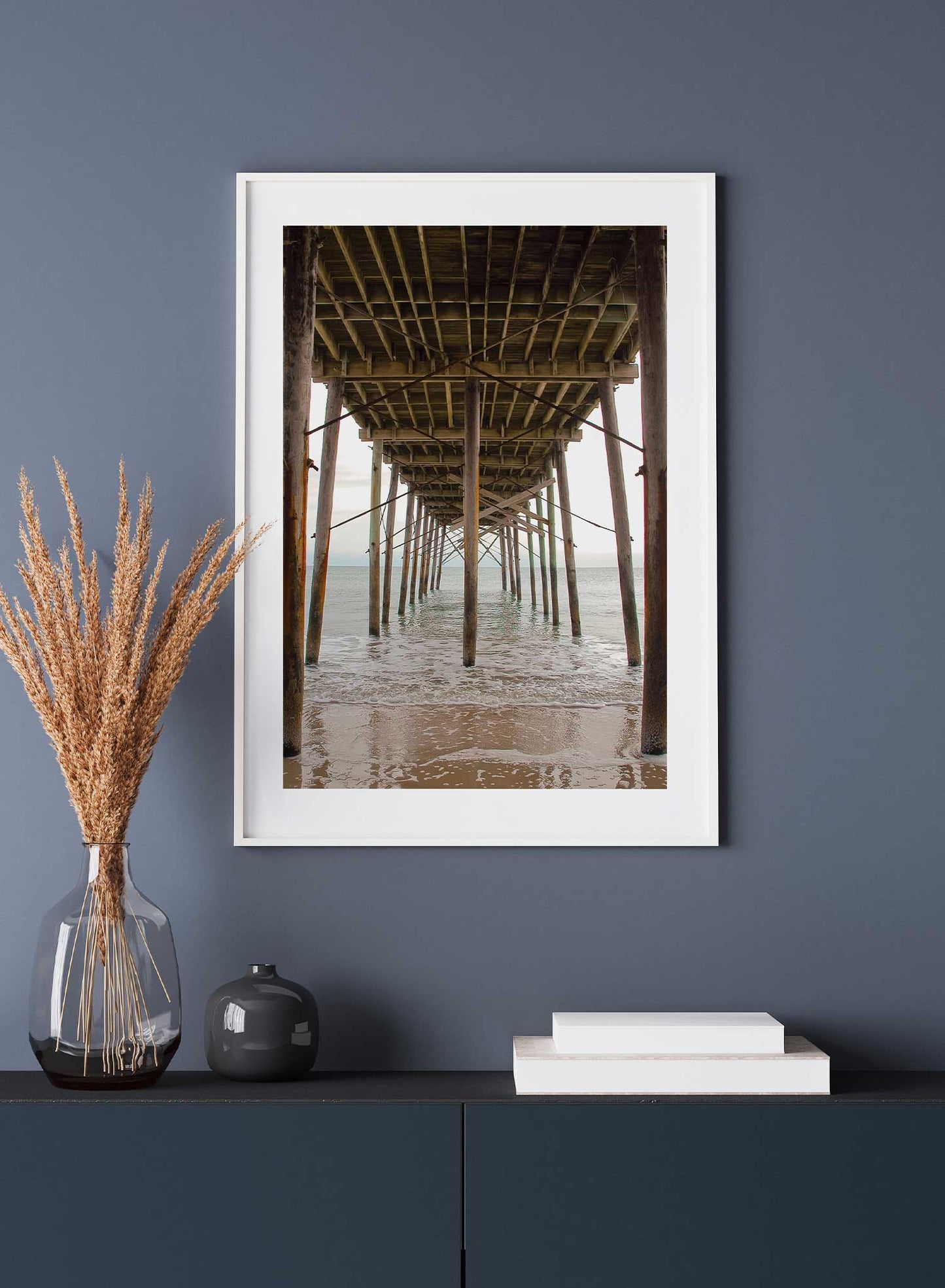 Beach House is a minimalist photography of an underview of a beach dock where waves are calmly flowing under by Opposite Wall.