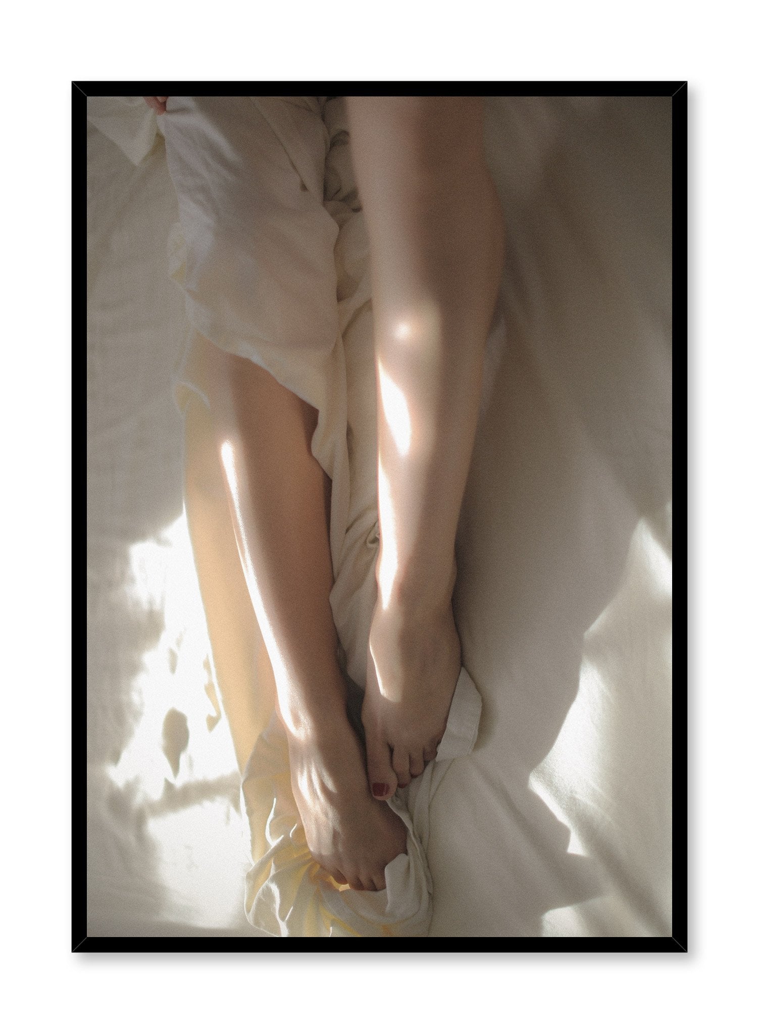 "Between the Sheets" is a minimalist beige and white photography poster by Opposite Wall of a woman’s nude legs, and feet in white bed sheets.