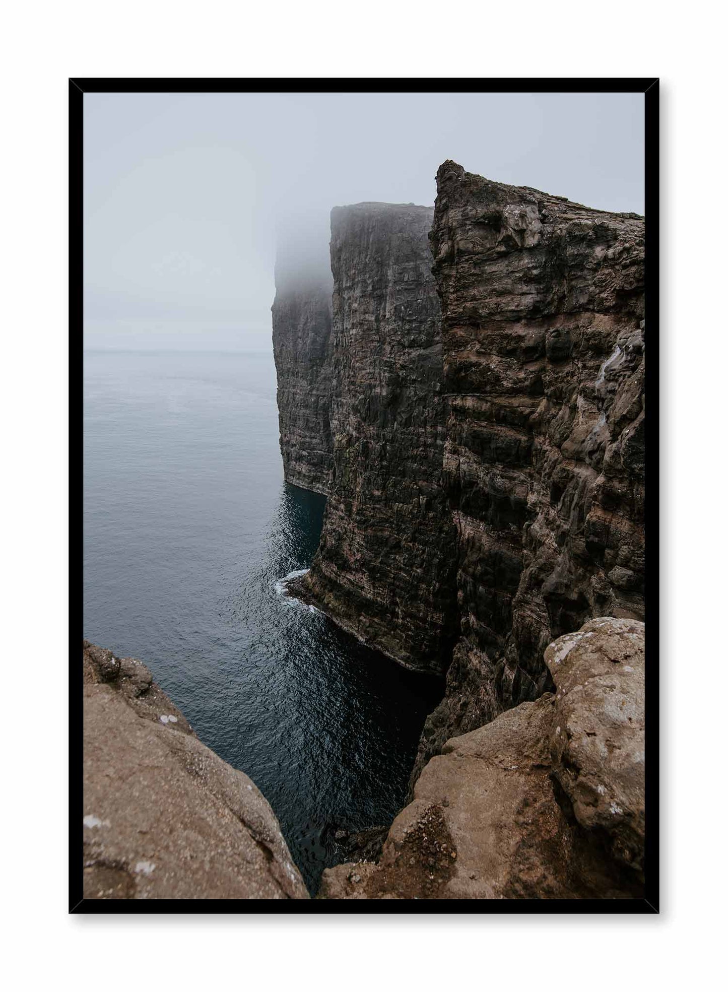 Steep' is a landscape photography poster by Opposite Wall of a rocky cliff overlooking a vast body of water and bathing in cloudy mist.