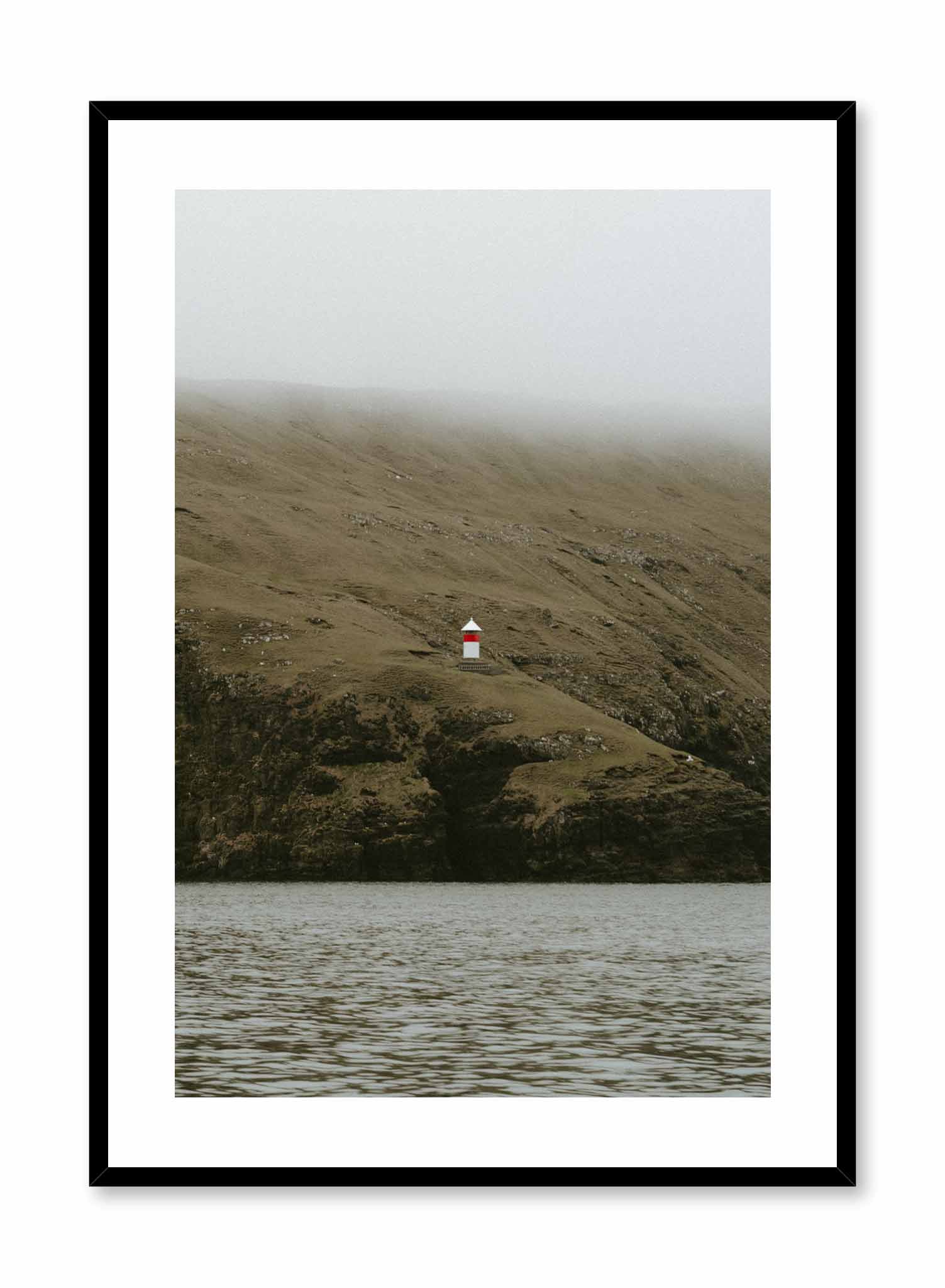 Lone Lighthouse' is a landscape photography poster by Opposite Wall of a red and white lighthouse over foggy lush green hills overlooking the water.