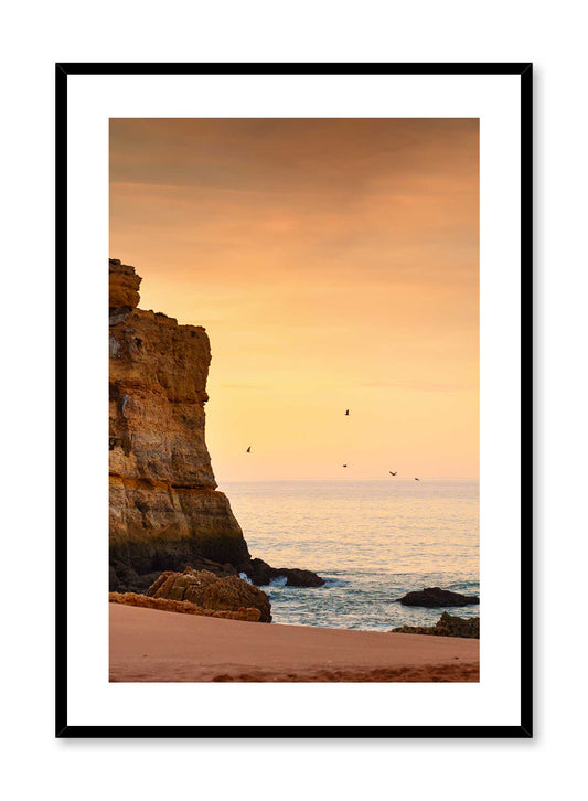 Creamsicle Sky is a minimalist photography of the sun setting on a beach where stands a rock formation with birds flying around by Opposite Wall.